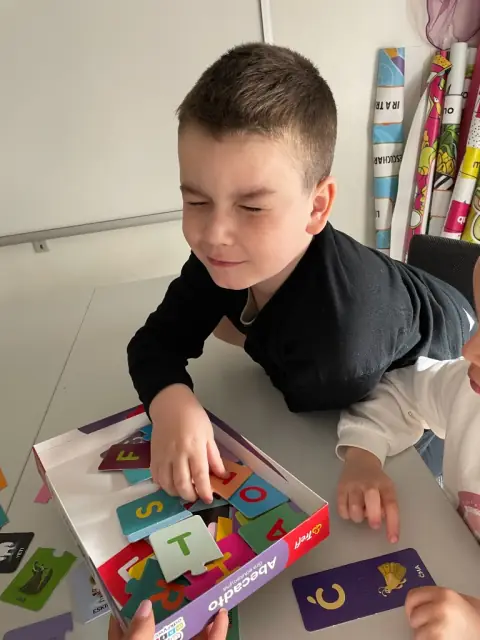 Chłopiec sięga po klocki z gry edukacyjnej Abecadło