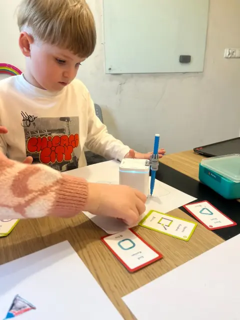 Chłopiec programuje robota rysującego figury geometryczne