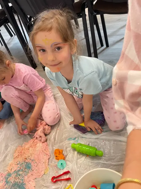Dziewczynka bawi się kolorowym slime podczas zajęć Sensorki