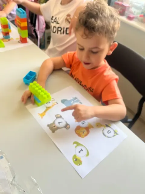 Chłopiec wskazuje liczby na karcie ze zwierzętami