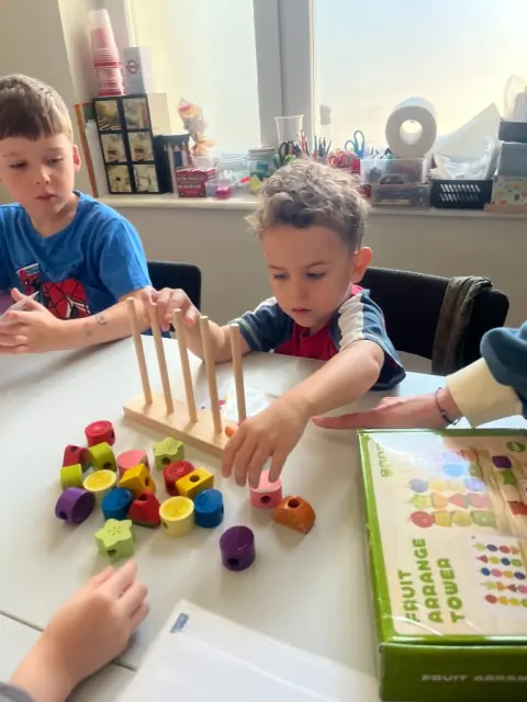 Chłopiec układa drewniane owoce na wieży Fruit Arrange Tower