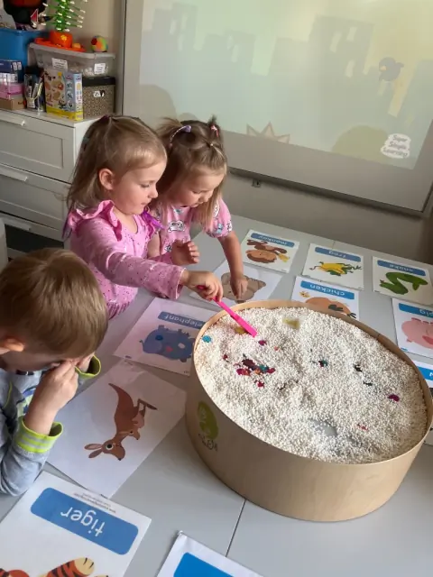Dzieci przy tacy sensorycznej i kartach elephant oraz kangaroo