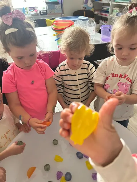 Dziewczynki bawią się plastikowymi owocami w misce z wodą